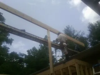 Carpenter setting a ridge beam over a new addition frame — Ice Dam Removal by Roofing Brothers in Monitor