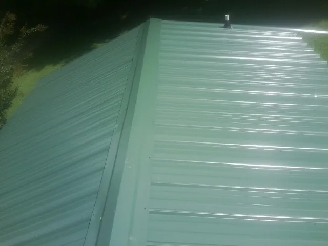 New green metal panels meeting at the ridge of a roof — Flat Roof Repair work by our crew in Monitor