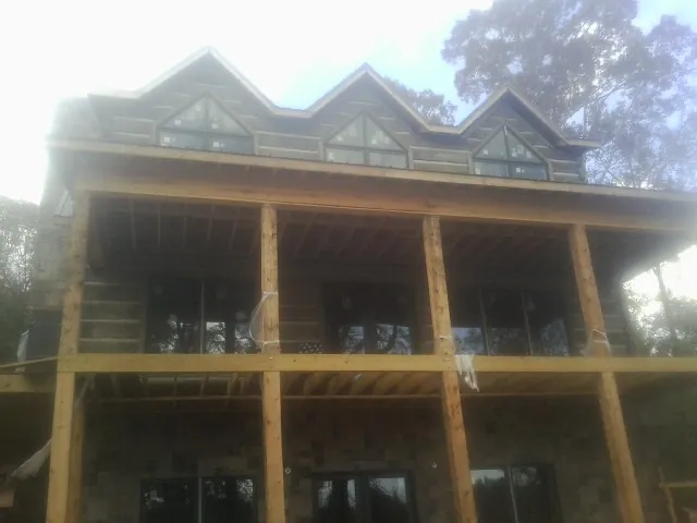 Dormers and porch framing on a large log home under construction — Roof Coating work by our crew in Monitor