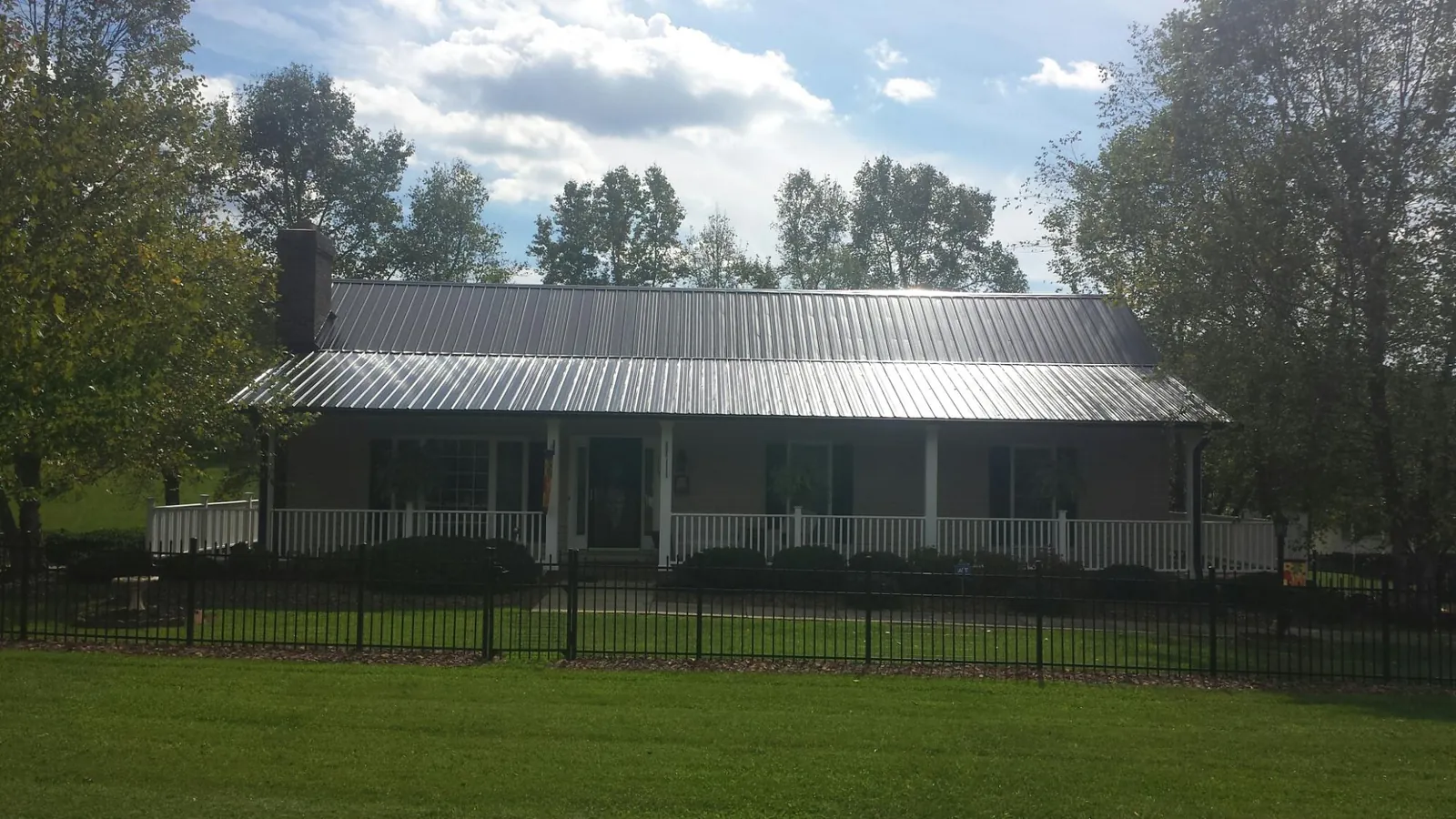 Gray metal roof on a brick ranch with a full width front porch — Gutter Guard Installation work by our crew in Monitor